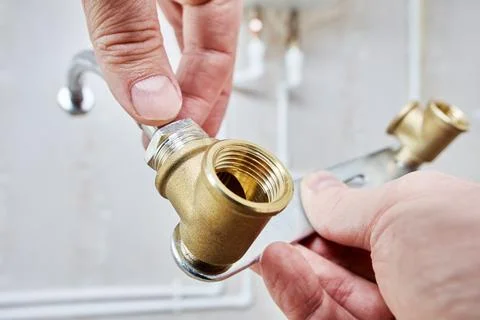 Hands assembling water pipe with metal bracket and connector. Stock Photos