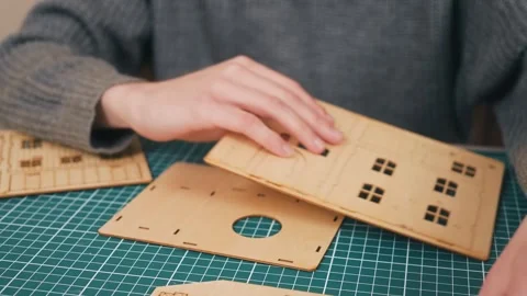 Hands assembling wooden house model kit on cutting mat. Building new home Stock-Footage 335144097