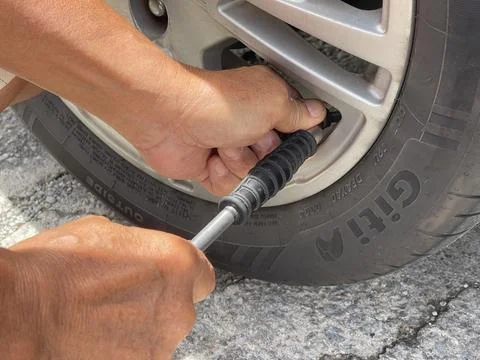 Hands attaching air pump nozzle to car tire valve during inflation Stock Photos