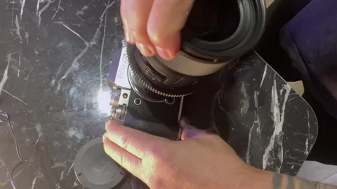 Hands attaching camera lens through adapter top view close-up, aligning mount Stockbeeldmateriaal 333650319