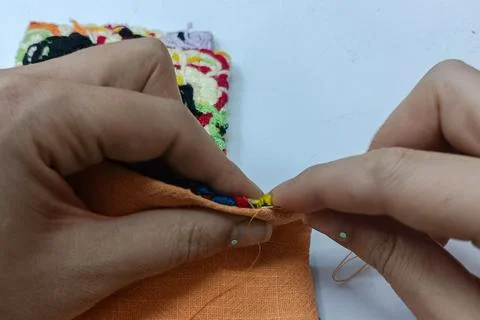 Hands attaching a colorful textile element to a handmade fiber art project.  Stock Photos
