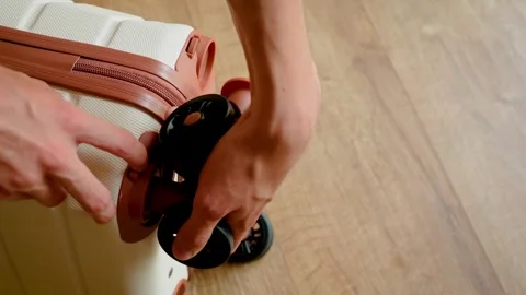 Hands attaching detachable wheels back onto hard shell cabin luggage after Video stock 343511729