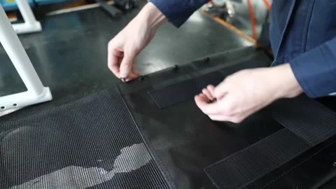 Hands attaching hook and loop strips to black wheelchair seat panel on workbench 스톡 동영상 347720048