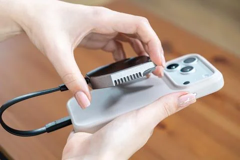 Hands attaching a magnetic SSD to a smartphone for mobile content creation, Stock Photos