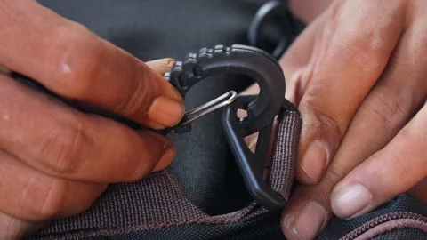 Hands attaching a plastic strap hook to a backpack strap Stock-Footage 339044327