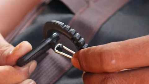 Hands attaching a plastic strap hook to a backpack strap Stock Footage 339044328
