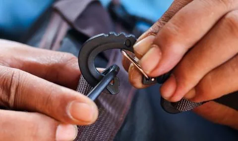 Hands attaching a plastic strap hook to a backpack strap Stock Photos
