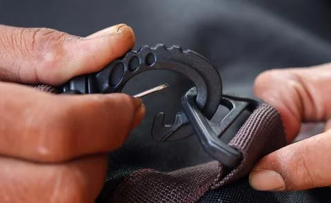 Hands attaching a plastic strap hook to a backpack strap Stock Photos