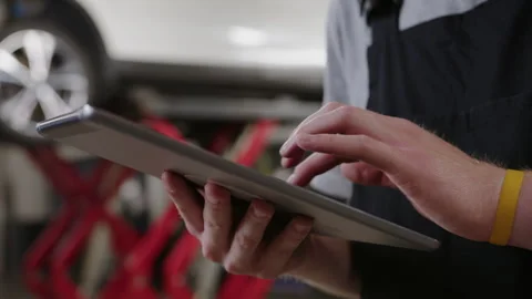 Hands of an auto electrician with a tablet. Diagnostics and repair of cars Stock Footage 253390575