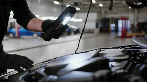 Hands of an auto mechanic with a flashlight who looks at technical fluids Stock Footage 221547246
