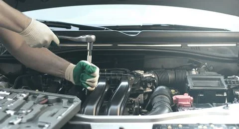 Hands of an auto mechanic with a socket wrench in the engine compartment of a Stock Photos