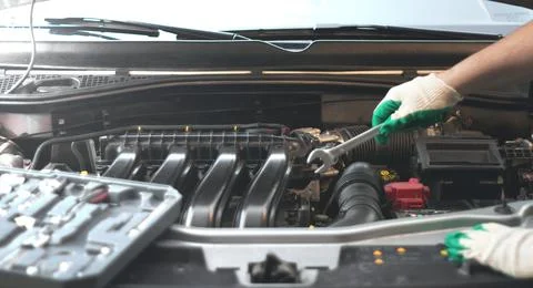 Hands of an auto mechanic with a socket wrench in the engine compartment of a Stock Photos