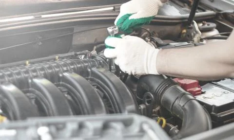 Hands of an auto mechanic with a socket wrench in the engine compartment of a Stock Photos