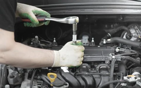 Hands of an auto mechanic with a socket wrench in the engine compartment of a Stock Photos