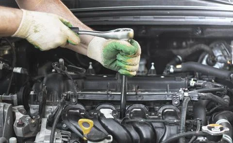 Hands of an auto mechanic with a socket wrench in the engine compartment of a Foto stock