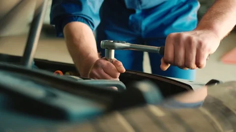 Hands of auto mechanic using nut socket wrench for nuting of the screwed under Stock Footage 76328349