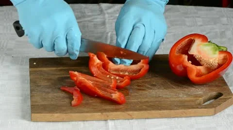 Hands with azure glove cutting red pepper Stock Footage