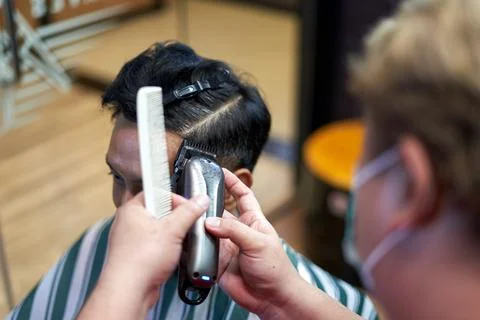 Hands of a baber using an electric razor to cut the hair of a client Stock Photos