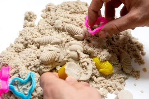 Hands on the background of kinetic sand. construction of turrets. Фото