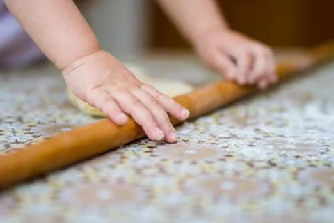 Hands baking dough with rolling pin on table. little chef  bake in kitchen. Stock Photos