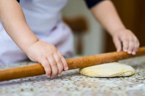 Hands baking dough with rolling pin on table. little chef  bake in kitchen. Stock Photos