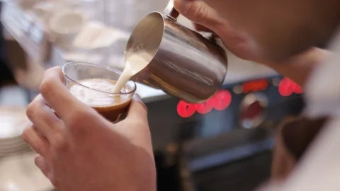 Hands of a barista making a pattern into a coffee drink using milk Stock Footage 87577855
