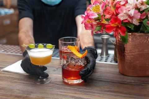 The hands of the bartender in protective gloves serve cocktails, close up Stock Photos
