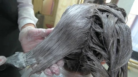 Hands of beautician dyeing hair. Stock Footage