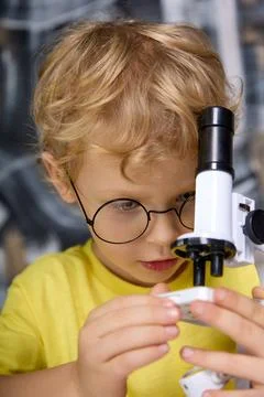 In the hands of a bespectacled boy a real microscope with a tube of black color Stock Photos