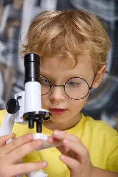 In the hands of a bespectacled boy a real microscope with a tube of black color Stock Photos