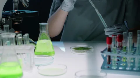 Hands of Biochemist Dropping Blue Liquid onto Green Cell Culture in Petri Dish 動画素材 280834626