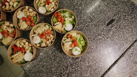 Hands in black gloves arrange fresh salad bowls with chicken, tomatoes, and Stock Footage 340172612