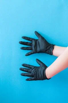 Hands with black gloves on blue background. Stock Photos