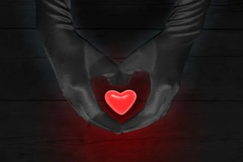 Hands in black gloves creating a form of heart with glowing red candy Stock Photos