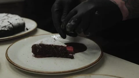  hands in black gloves decorating a chocolate dessert with strawberries Stock Footage 300028380