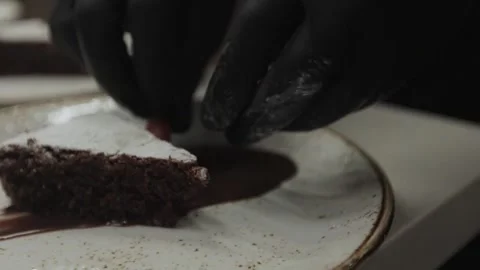  hands in black gloves decorating a chocolate dessert with strawberries Stock Footage 300028381