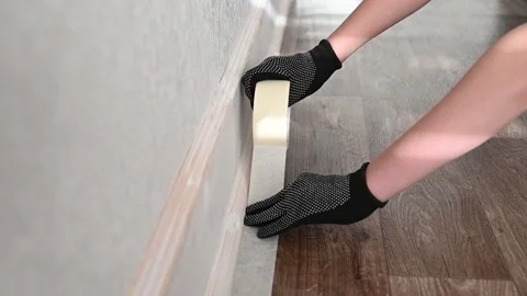 Hands in black gloves gluing construction tape to the floor in the apartment. Stock Footage 165951153
