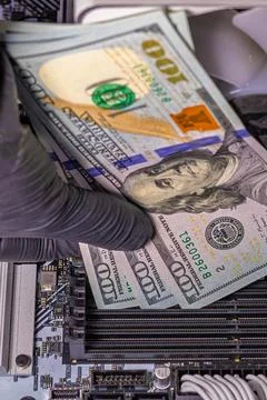 Hands in black gloves inserting 100-dollar bills into empty RAM slots on a .. Stock Photos