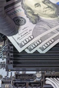 Hands in black gloves inserting 100-dollar bills into empty RAM slots on a .. 写真素材