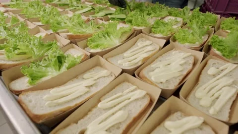 Hands in black gloves place fresh lettuce leaves on sandwich bread with Stock Footage 340172271