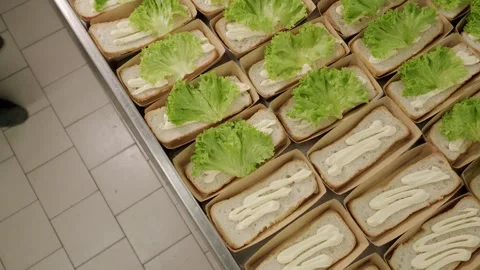 Hands in black gloves place fresh lettuce leaves on sandwich bread with Stock Footage 340172358