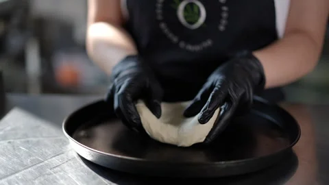 Hands in Black Gloves Shaping Pizza Dough on a Baking Tray Stock Footage 296587336