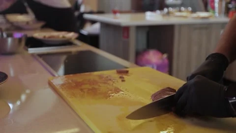 Hands in black gloves slicing meat on a wooden cutting board. Stock Footage 300028219