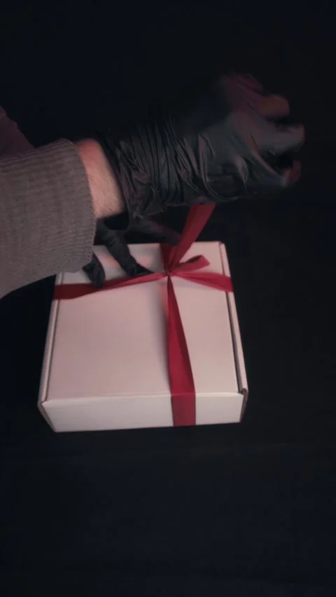Hands in Black Gloves Tying Red Ribbon on White Gift Box Dark Background Stock Footage 323453372