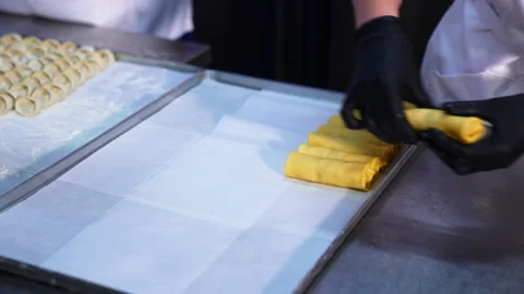 Hands in black latex gloves put the rolled crepes with stuffing on a tray. Stock Footage 196222350