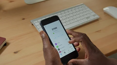 Hands of Black Man Using Mobile Banking Application on Smartphone at Desk Stock Footage 347654412