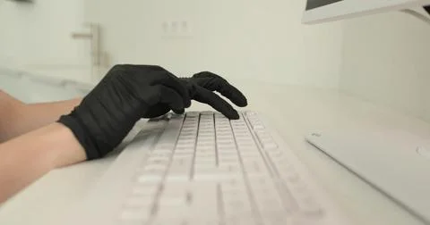 Hands in black nitrile gloves using keyboard while doing work in clinic. Me.. Stock Photos