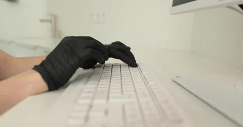 Hands in black nitrile gloves using keyboard while doing work in clinic. Me.. Stock Photos