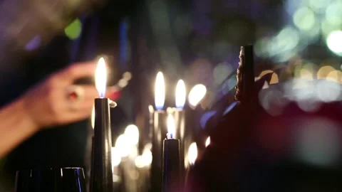 Hands with black wine glasses join against a background of burning black candles Stock Footage 131378816