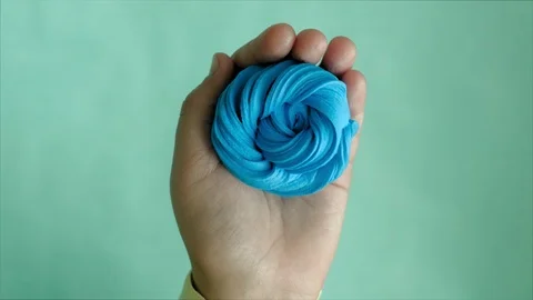 Hands on a blue background use multi-colored soft clay for modeling. Creative Stock Footage 111245683